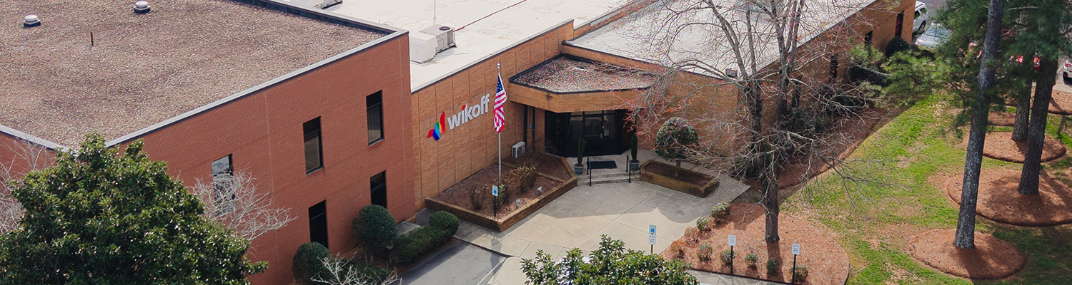 Aerial view of a brick office building with the Univar Solutions logo, American flag, and trees surrounding the entrance.