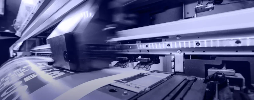 Close-up of an industrial printer in operation, printing text onto a wide roll of material.