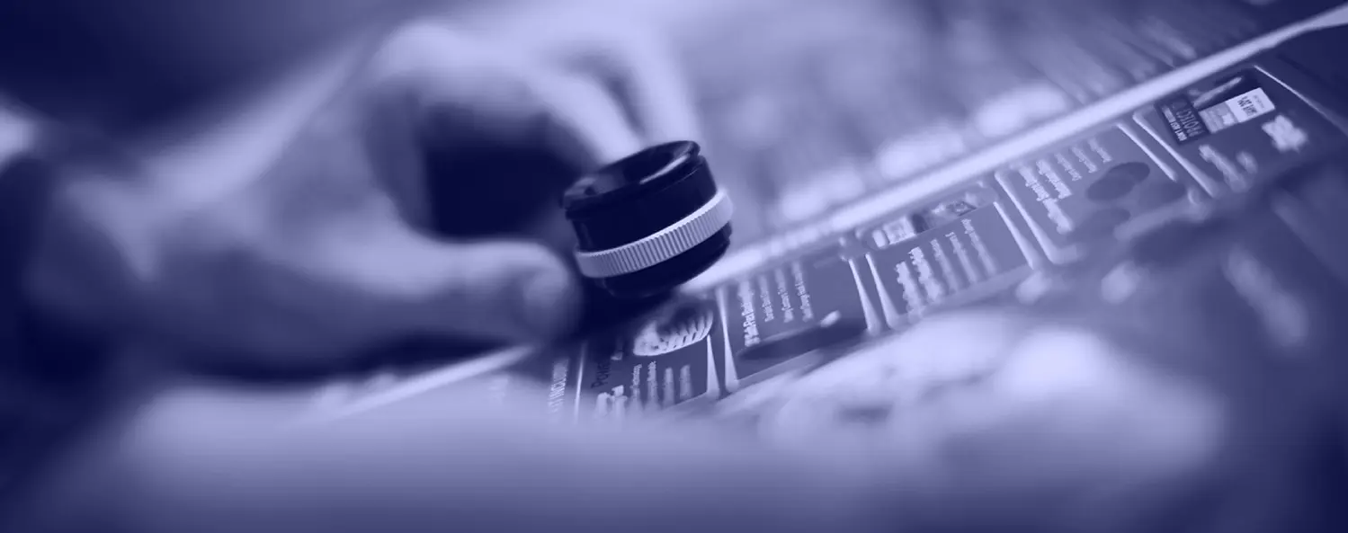 A hand uses a magnifying glass to closely examine printed text and images on a sheet of paper.