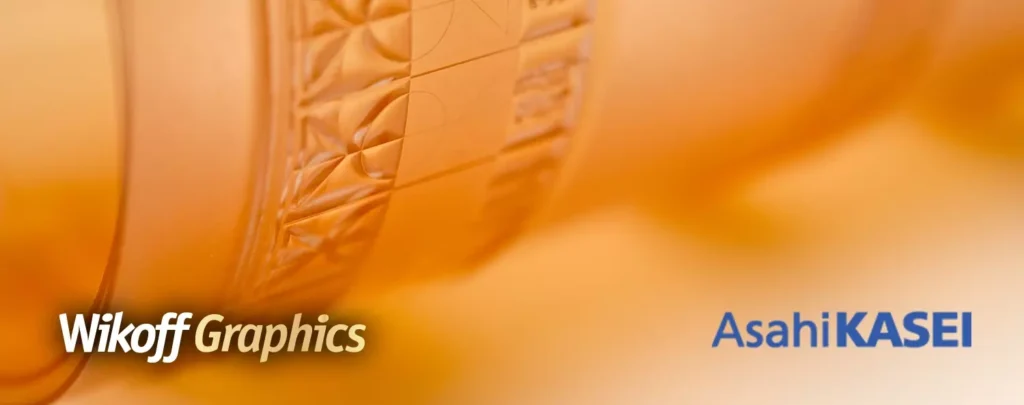 Close-up of an orange flexographic printing plate with Wikoff Graphics and Asahi KASEI logos on an orange background.