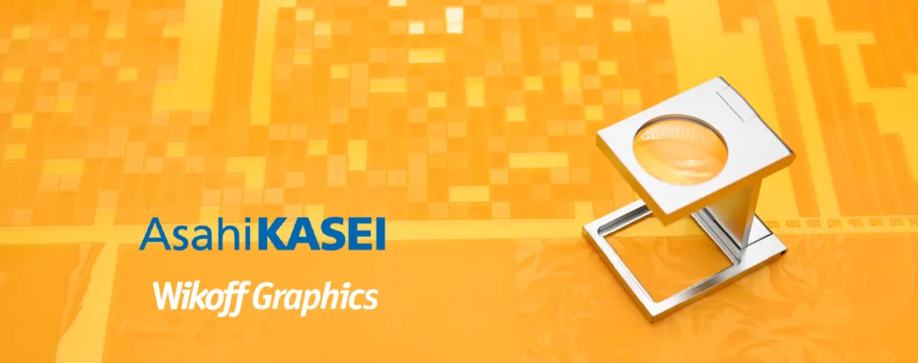 Magnifying glass on a yellow pixelated background with the text "Asahi KASEI" and "Wikoff Graphics" in blue and white fonts.